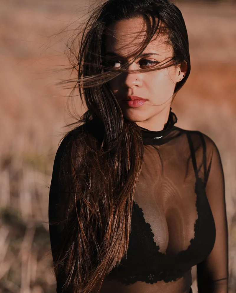 woman wearing black sheer top with hair blowing in wind