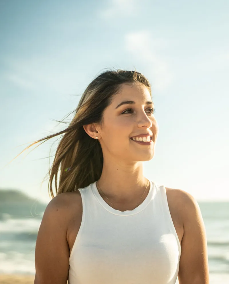 woman in white tank top walking on beach