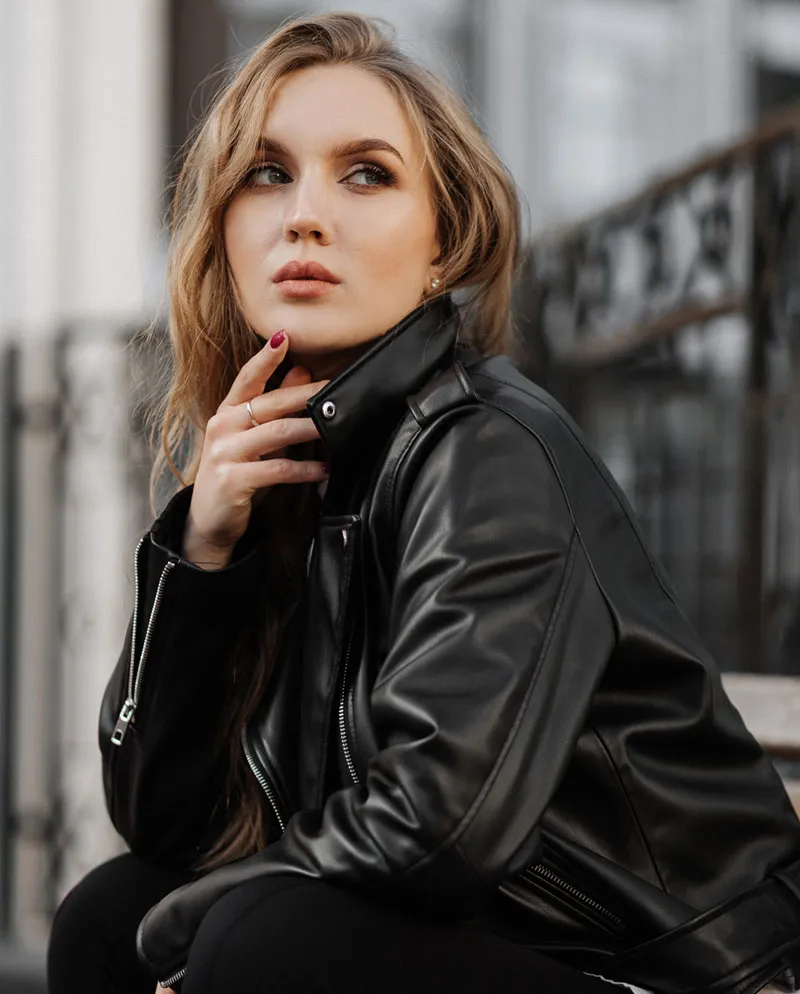 woman in leather jacket looking off outside