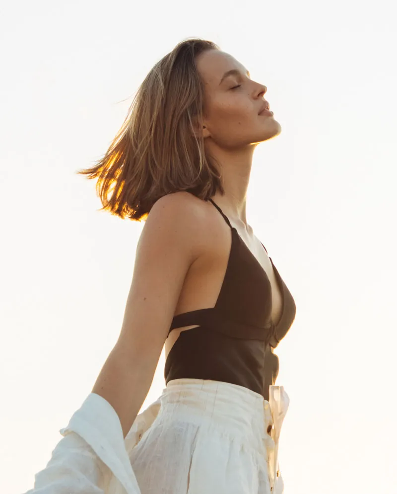 woman with jacket hanging off arms basking in the sun