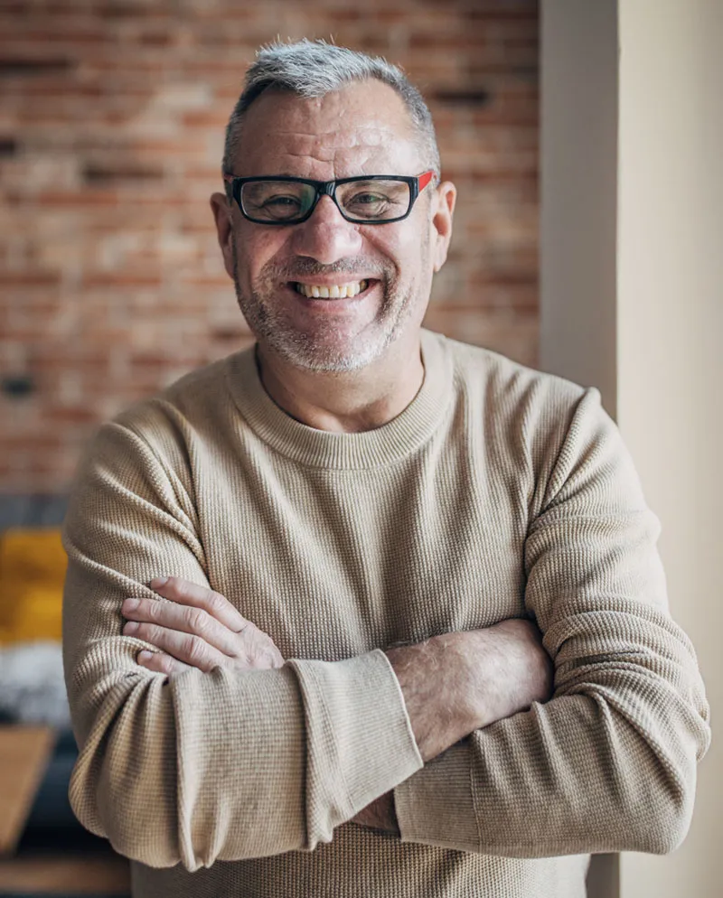 middle aged man with glasses and arms crossed smiling